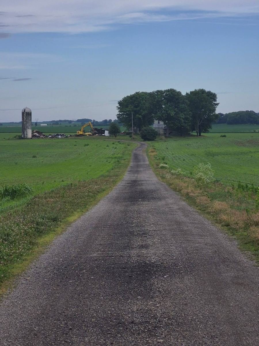 Same lane with the barns torn down into a debris pile next to the silo