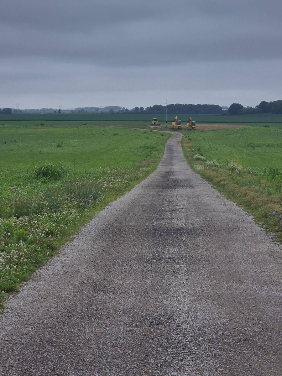 Same lane with a bulldozer and two excavators on a cleared dirt pad