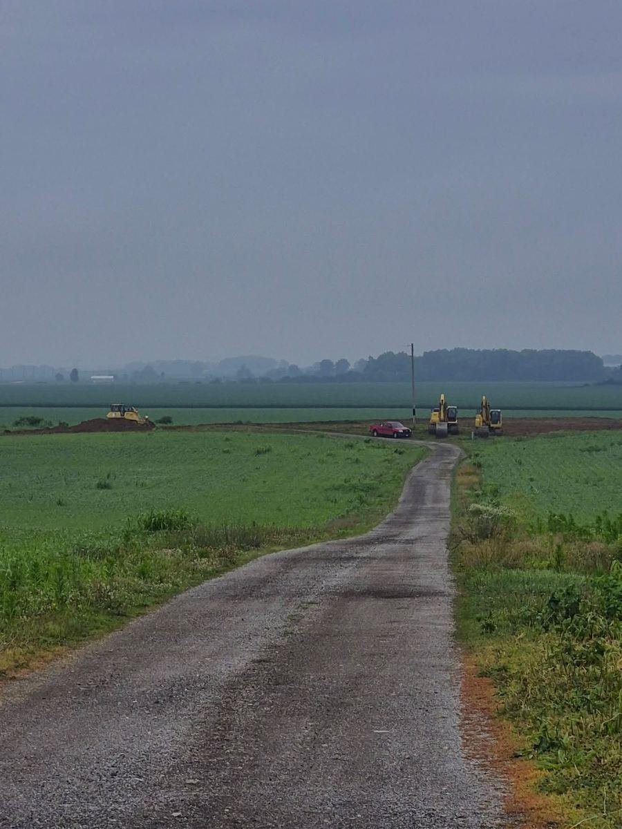 Bulldozer grading the cleared ground with excavators and a pickup nearby