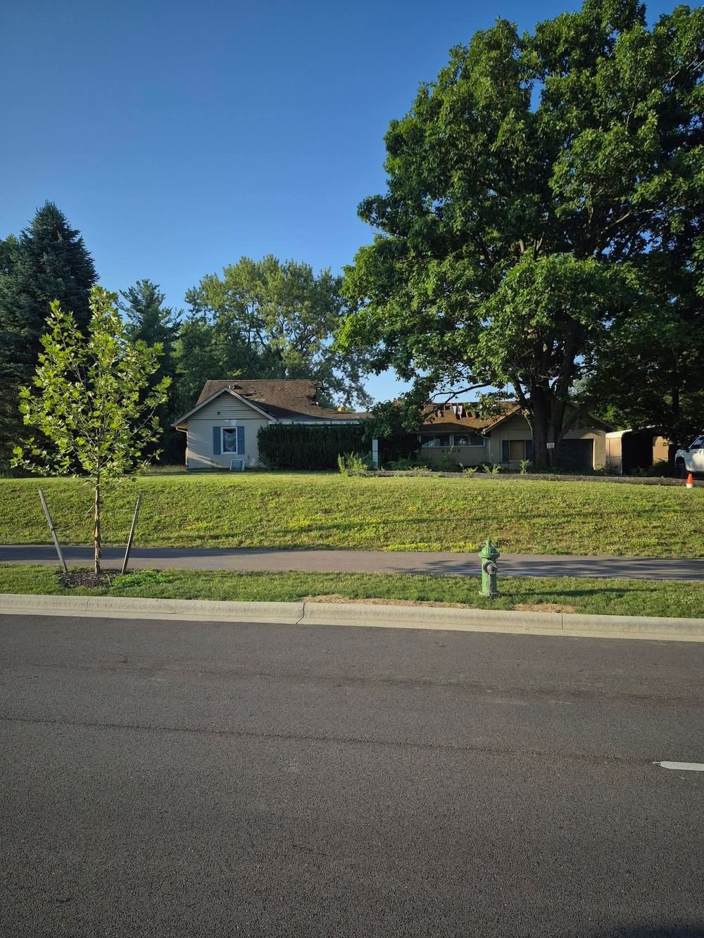 Vacant ranch house with a damaged roof seen from the street