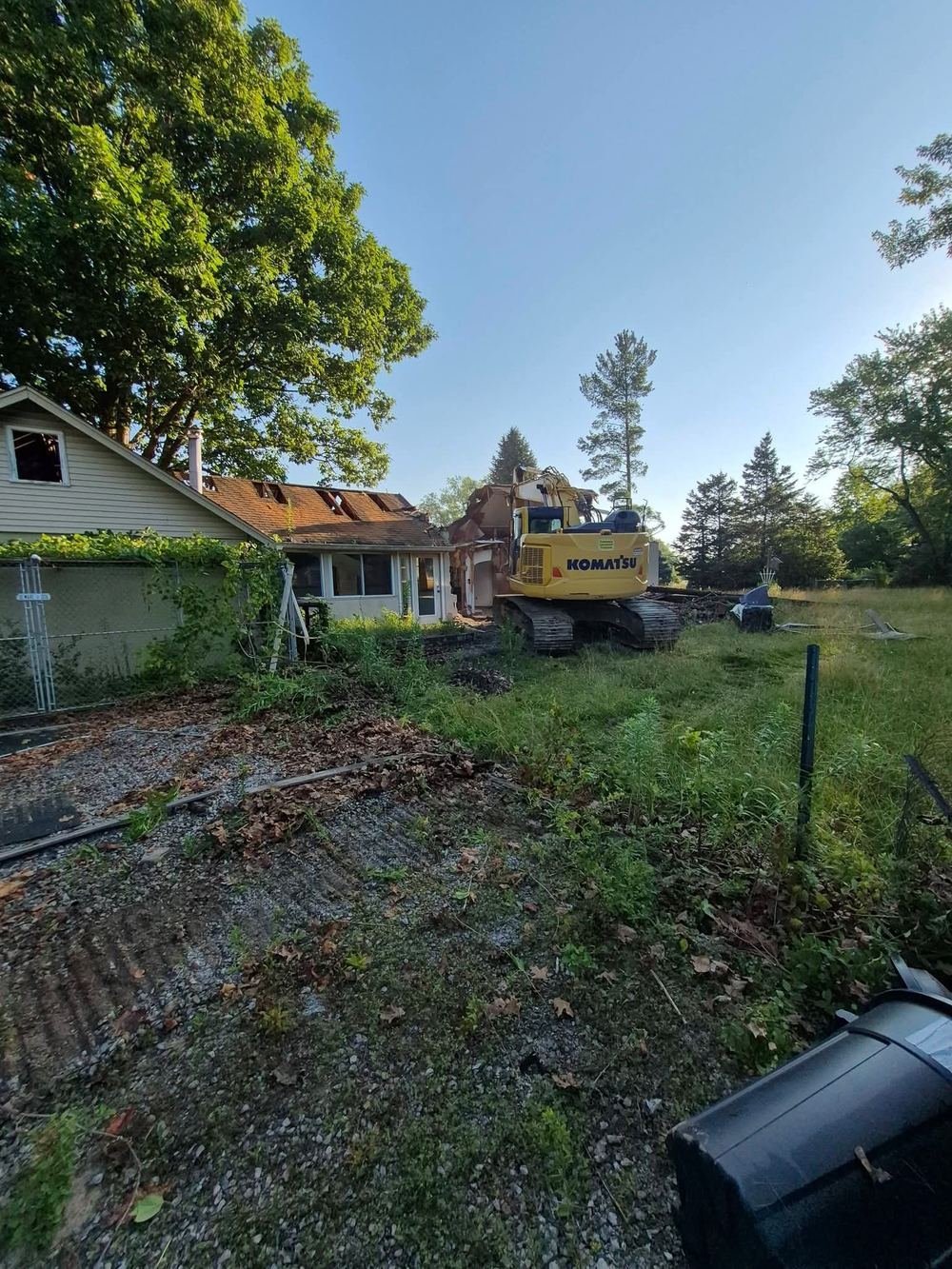 Komatsu excavator tearing into the back of a house